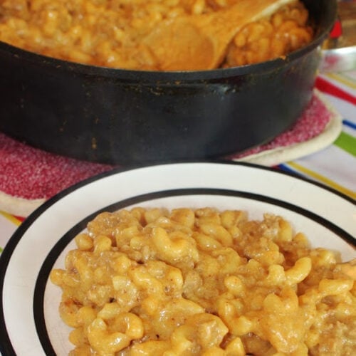 Homemade Hamburger Helper served on a white plate in front of the pot with wooden spoon