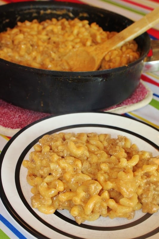 Homemade Hamburger Helper served on a white plate in front of the pot with wooden spoon