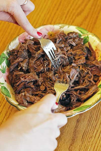 Shredded beef and 2 forks in a bowl