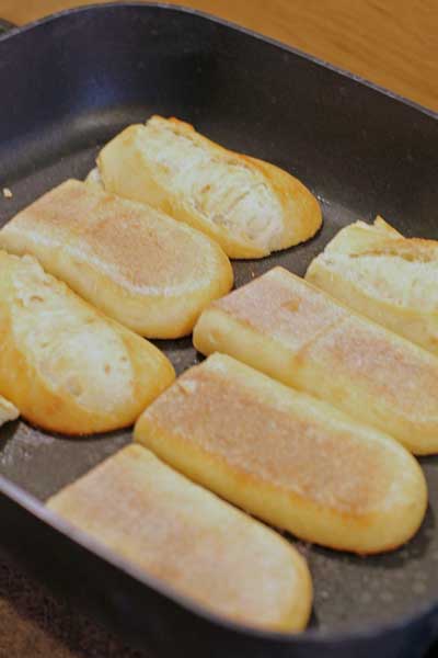 hoagie rolls toasting on a skillet