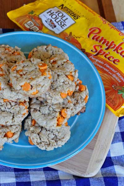 Pumpkin Spice Oatmeal Cookies sitting on a round blue plate next to a package of pumpkin spice chips from the store