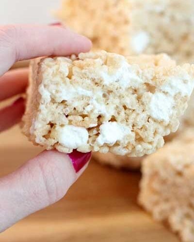 Hand holding Bakery Style Rice Krispie Bars with blurred background