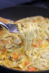 A bite of One Skillet Creamy Chicken Pasta on a fork being lifted from the skillet