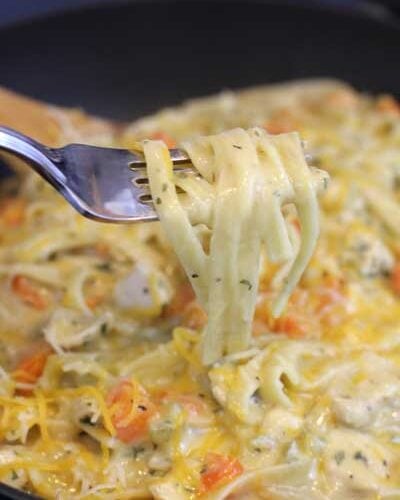 A bite of One Skillet Creamy Chicken Pasta on a fork being lifted from the skillet
