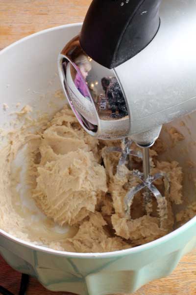 Hand mixer making dough for cream cheese snickerdoodle in a white bowl