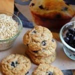 Blueberry cookies stacked next to bowls of blueberries and box of mix