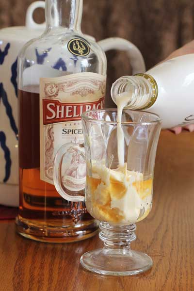 Rum Chatta being poured into a clear glass on a wood table