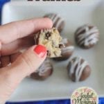 No Bake Cookie Dough Truffles text overlay with a hand holding a truffle already bitten above a white plate with more truffles