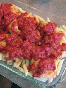 Sauce on top of chicken over noodles in a glass pan