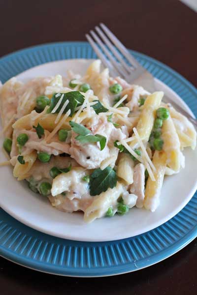 One Skillet Chicken Alfredo and Peas on a round white plate with a fork