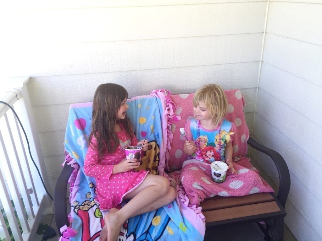 Sisters laughing sitting on a bench with ice cream