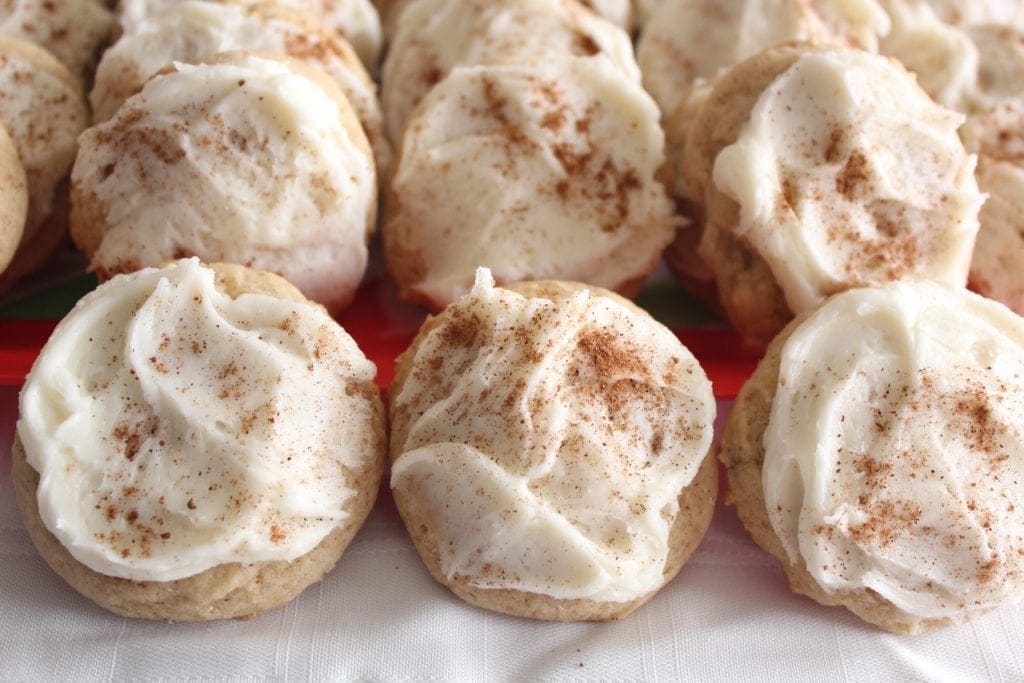 Round tan cookies with white eggnog frosting sprinkle with cinnamon on a large platter