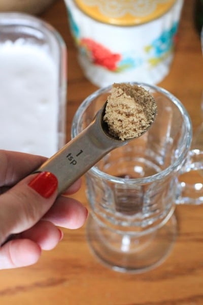 One teaspoon of brown sugar being measured for Authentic Irish Coffee in clear glass 