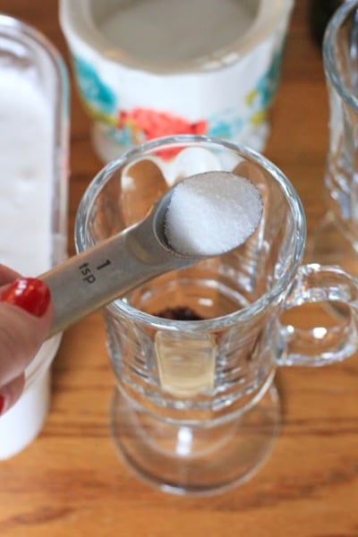 one teaspoon of sugar being measured for Authentic Irish Coffee in clear glass 