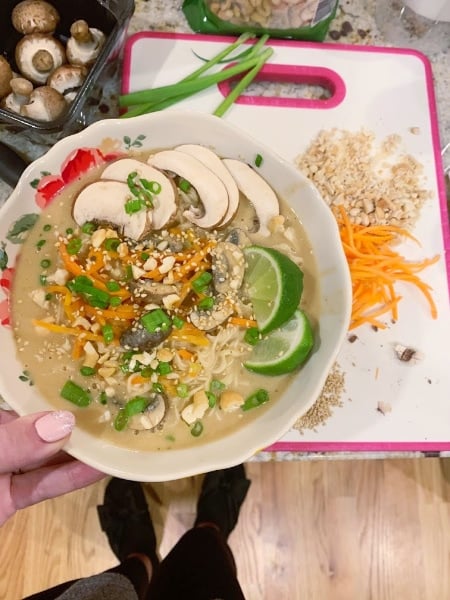 Spicy Thai Vegetable Ramen in a bowl held above a cutting board with all the ingredients