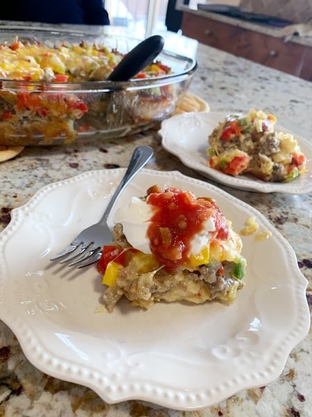 Make-Ahead Egg Bake served with sour cream and Salsa sitting on a white plate with fork