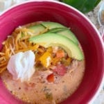 Close up shot of Creamy Chicken Fajita Soup in a bowl next to ingredients on a marble countertop