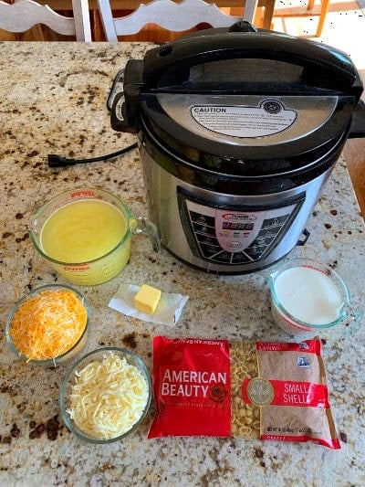 A pressure cooker, and all the ingredients needed for mac and cheese sitting together on a counter