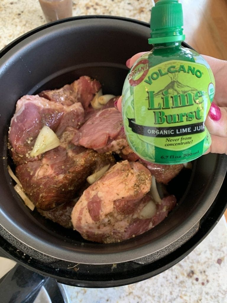 lime juice held above a slow cooker to makePulled carnitas 