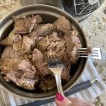 tender Pulled carnitas in a bowl being pulled apart with forks