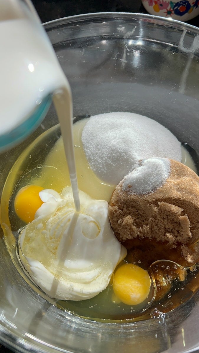 glass bowl with sugars, egg, and milk being poured in