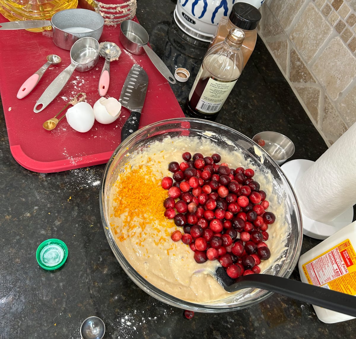 kitchen counter with bowl of batter and mixing items for glazed orange cranberry bread
