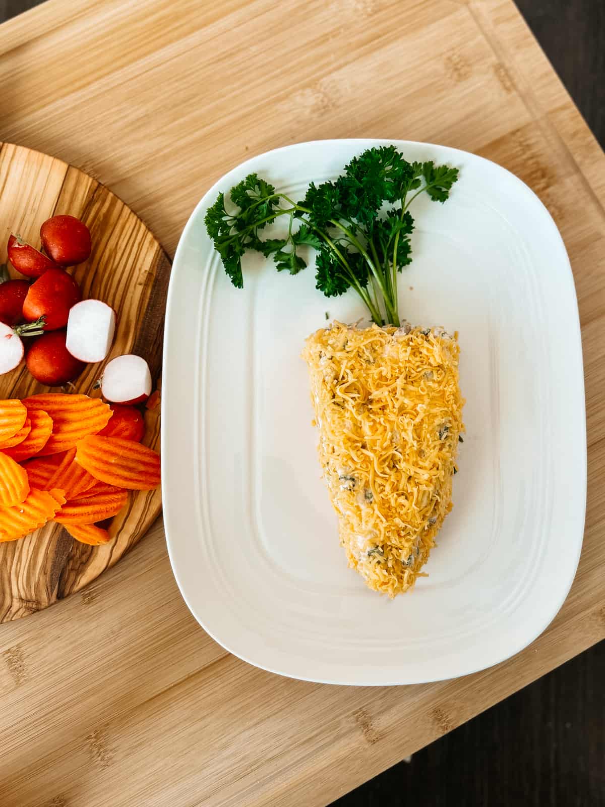 cheese ball shaped as a carrot on a white platter.