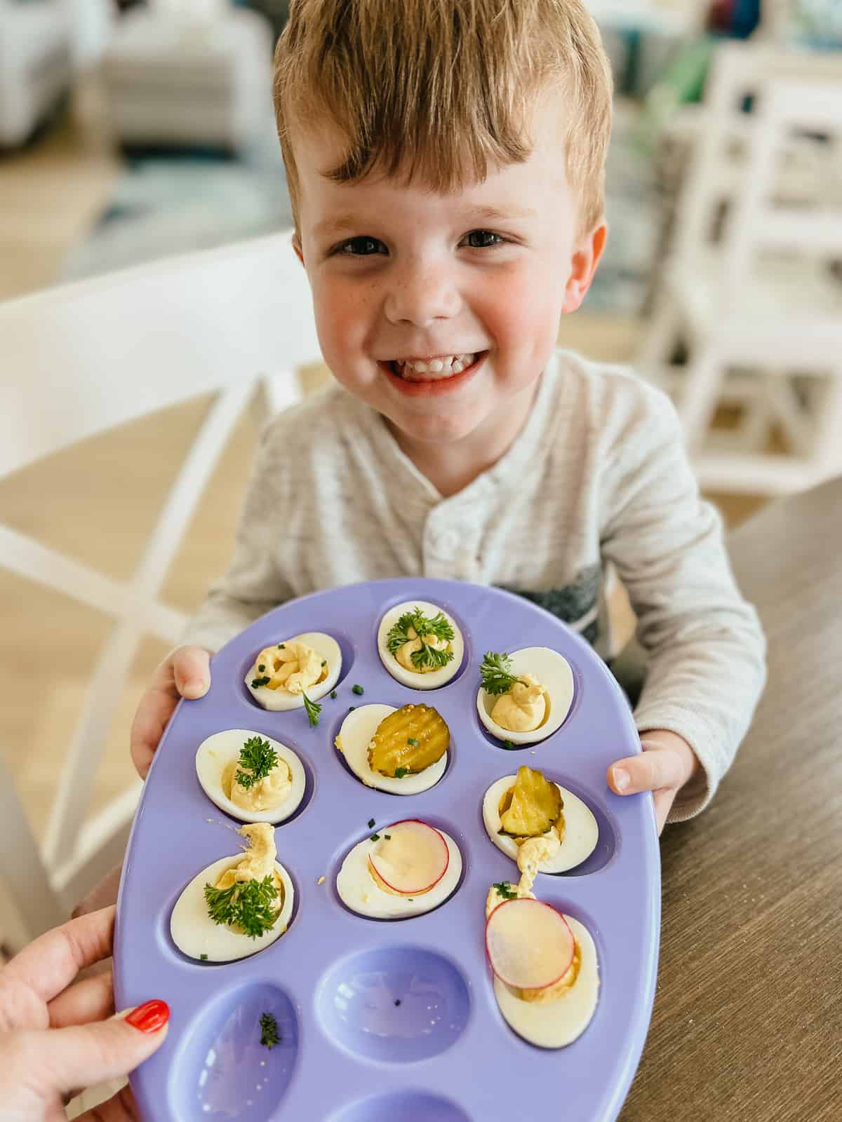 toddler holding an egg platter with garnished deviled eggs
