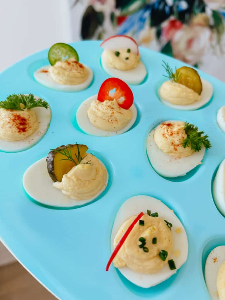 teal egg platter with deviled eggs with various garnishes