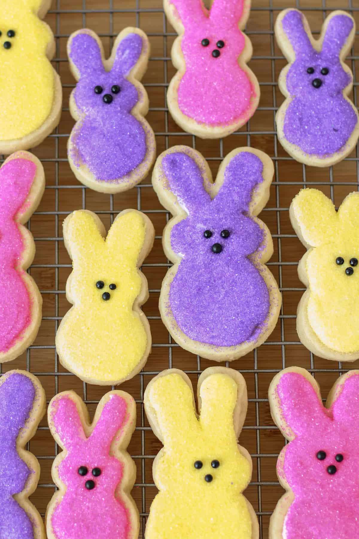 Yellow, purple, pink bunny peeps sugar cookies with sprinkles on a wire rack
