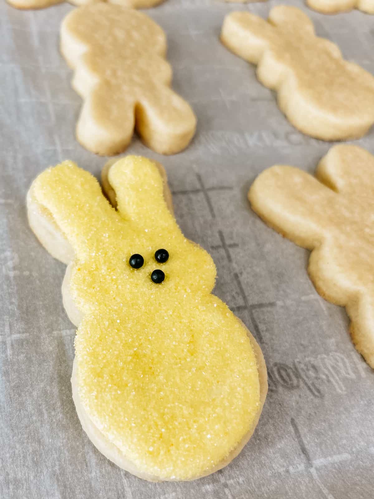 sugar cookies on a baking sheet, one decorated as a peeps sugar cookie with sprinkles.