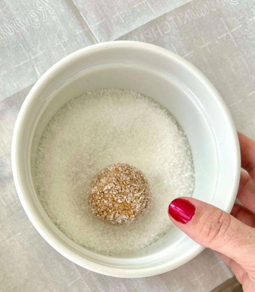 white dish with coarse sugar and a ball of cookie dough