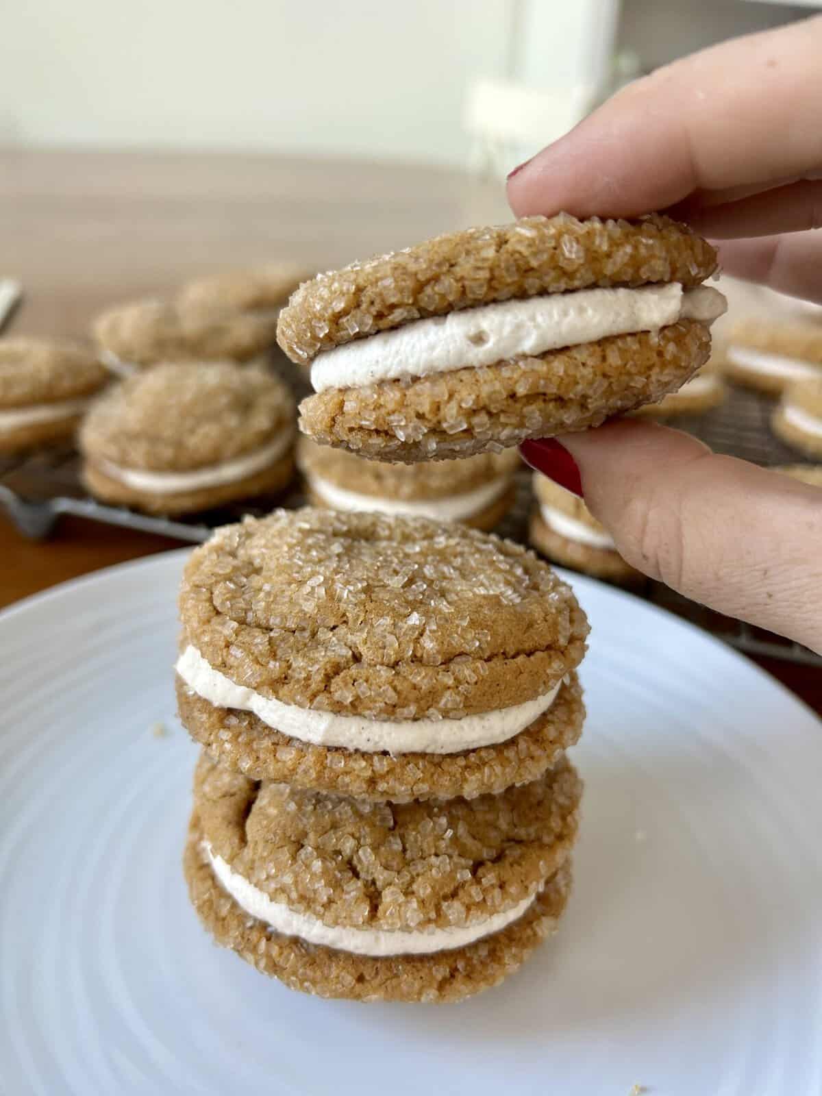 3 cookies stacked on a plate with one being held in hand