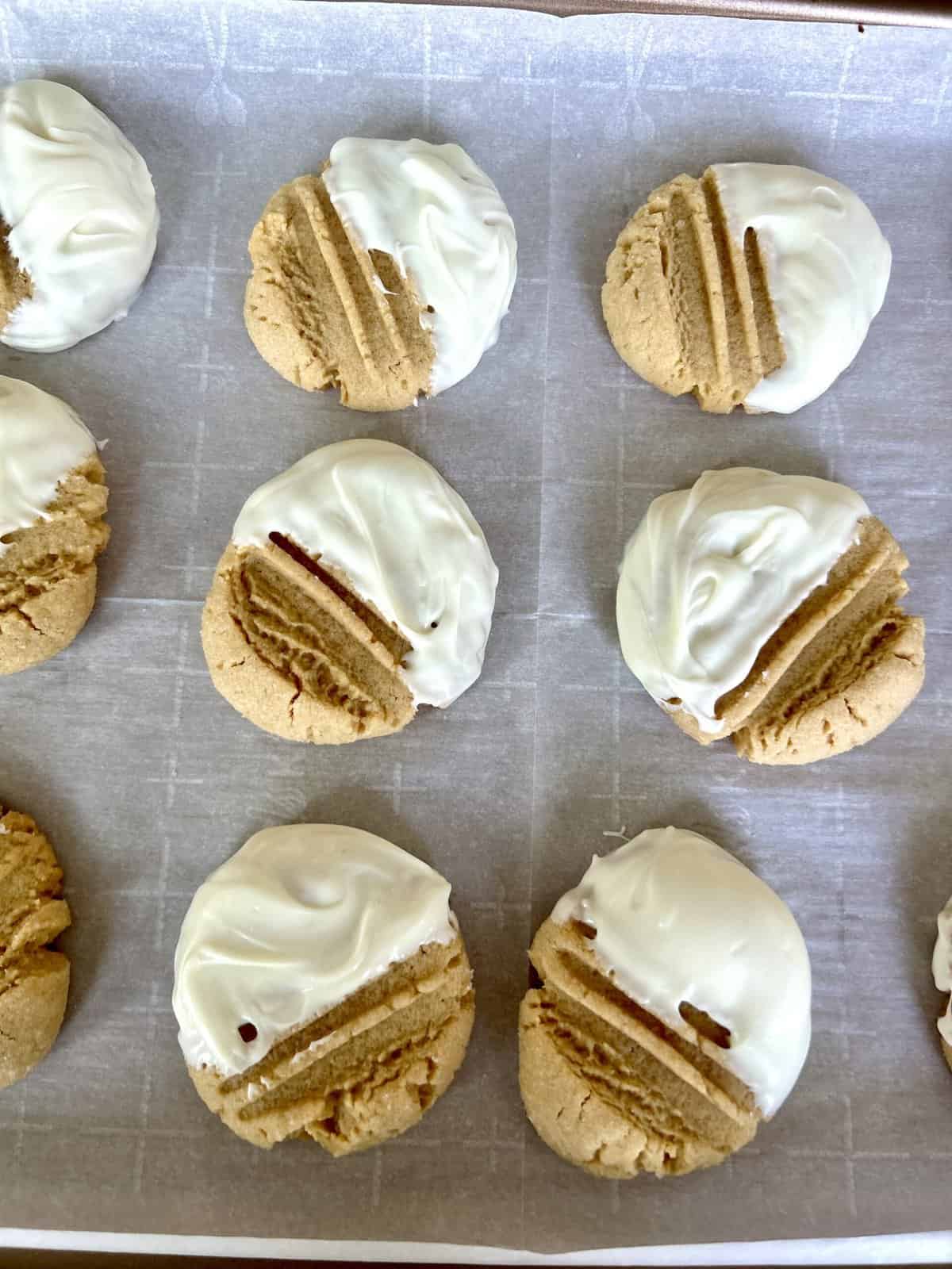 peanut butter cookies on a baking sheet dipped in white chocolate