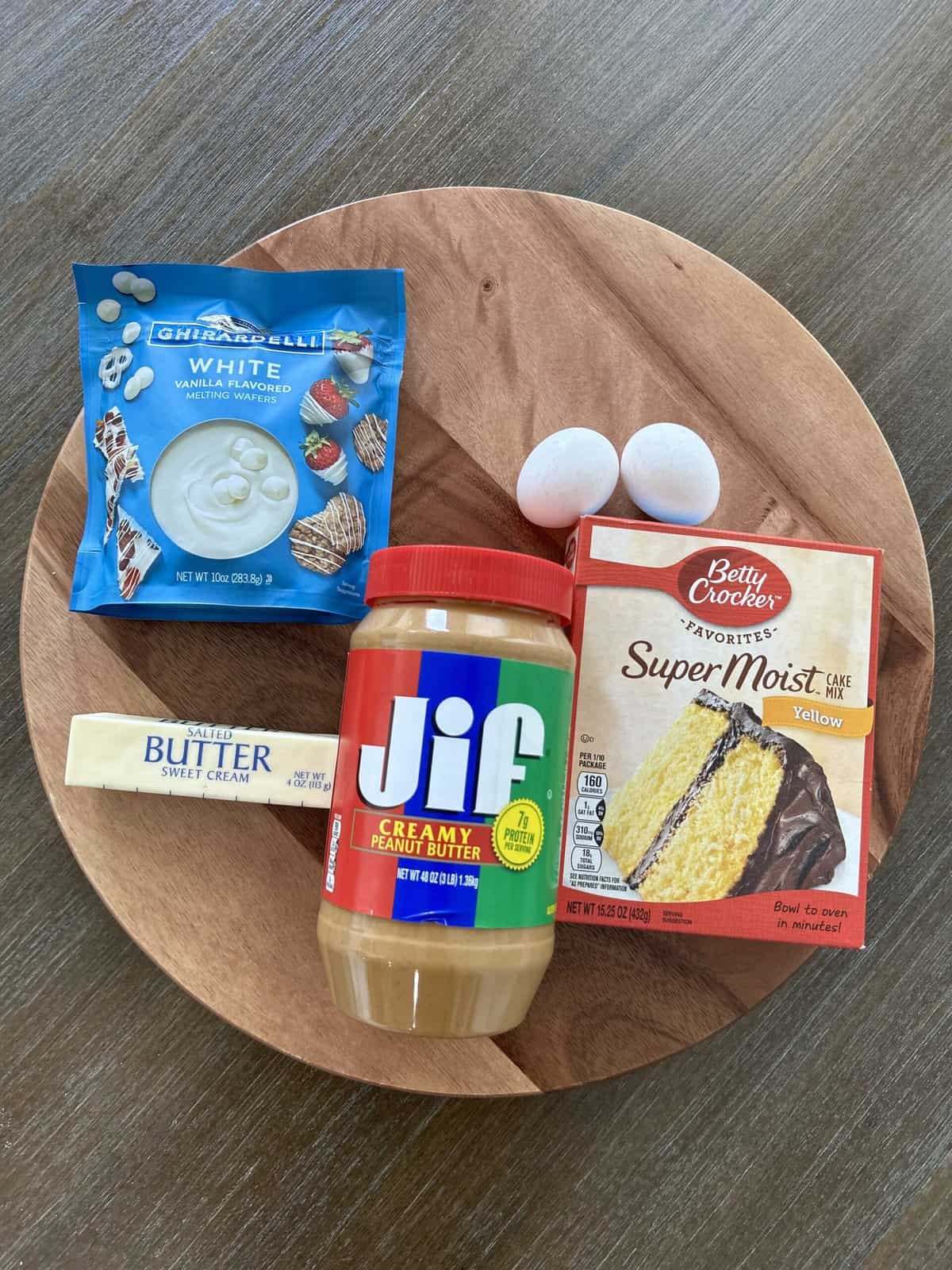 cake mix, peanut butter, 2 eggs, white chocolate, a stick of butter all in a flat lay